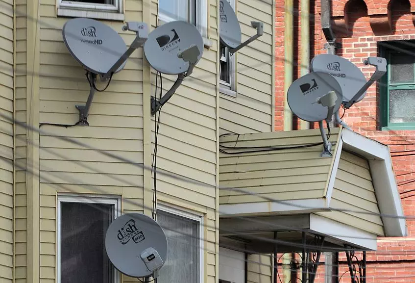 Multiple old satellite dishes mounted on a residential building